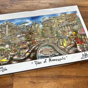 May include: A colorful art print titled Pubs of Minneapolis featuring a detailed cityscape illustration with various buildings, a yellow taxi, and a riverboat. The print includes a signature and the edition number 457/2500 on the white border.