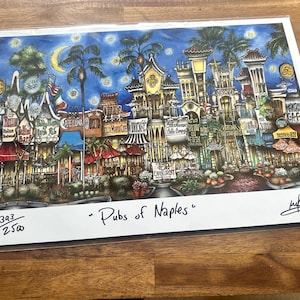 May include: A colorful illustration of a street scene in Naples, Florida, with a variety of shops and restaurants. The image is titled "Pubs of Naples" and is numbered 393/2500.