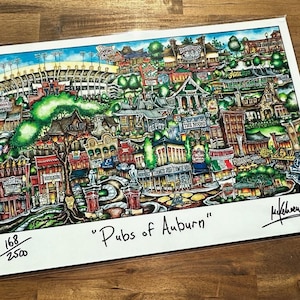May include: A colorful illustration of a city scene with buildings, trees, and a stadium in the background. The illustration is titled "Pubs of Auburn" and is numbered 168/250.