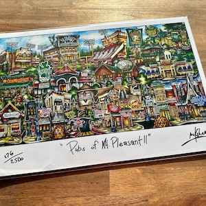 May include: A colorful print titled "Pubs of Mt. Pleasant II" featuring a detailed illustration of a town with various buildings, shops, and signs. The artwork is signed and numbered 176/2500.