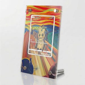 Könnte beinhalten: Ein transparenter Acryl-Displayrahmen mit einer Sammelkarte, die eine Mimikyu-Charakterillustration im Stil des Schreis zeigt. Die Karte enthält japanischen Text, einen 70-KP-Wert und lebendige, wirbelnde rote, orange und blaue Farben.
