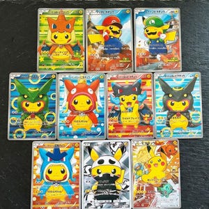 Könnte beinhalten: Zehn Pokémon-Sammelkarten mit Pikachu in verschiedenen Kostümen. Die Karten haben farbenfrohe Illustrationen und japanischen Text. Pikachu wird in verschiedenen Posen und Umgebungen dargestellt.