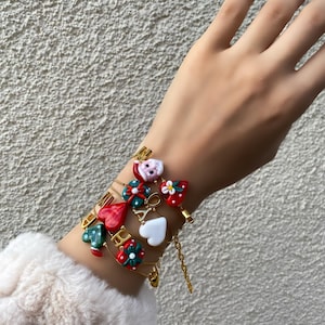 Paquete de regalo de gorro navideño con forma de corazón rojo y pulseras de acero con letras temáticas de Papá Noel y la suerte