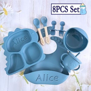 May include: An 8 piece blue silicone baby feeding set with the name Alice personalised on the plate, bowl, and bib. The set includes a plate, bowl, bib, two spoons, two forks, and a sippy cup.