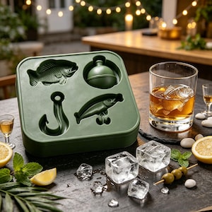 May include: A square, olive green silicone ice cube tray featuring four distinct molds shaped like a fish, a fishing bobber, a fishing hook, and a lure. Beside the tray sits a clear glass filled with amber liquid and a fish-shaped ice cube.