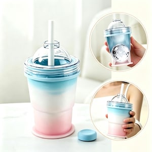 May include: A gradient tumbler featuring a blue, white, and pink color scheme with a clear dome lid and a white straw. The cup has a ribbed texture near the top and a matching blue circular cap sits separately on the surface next to the main cup.