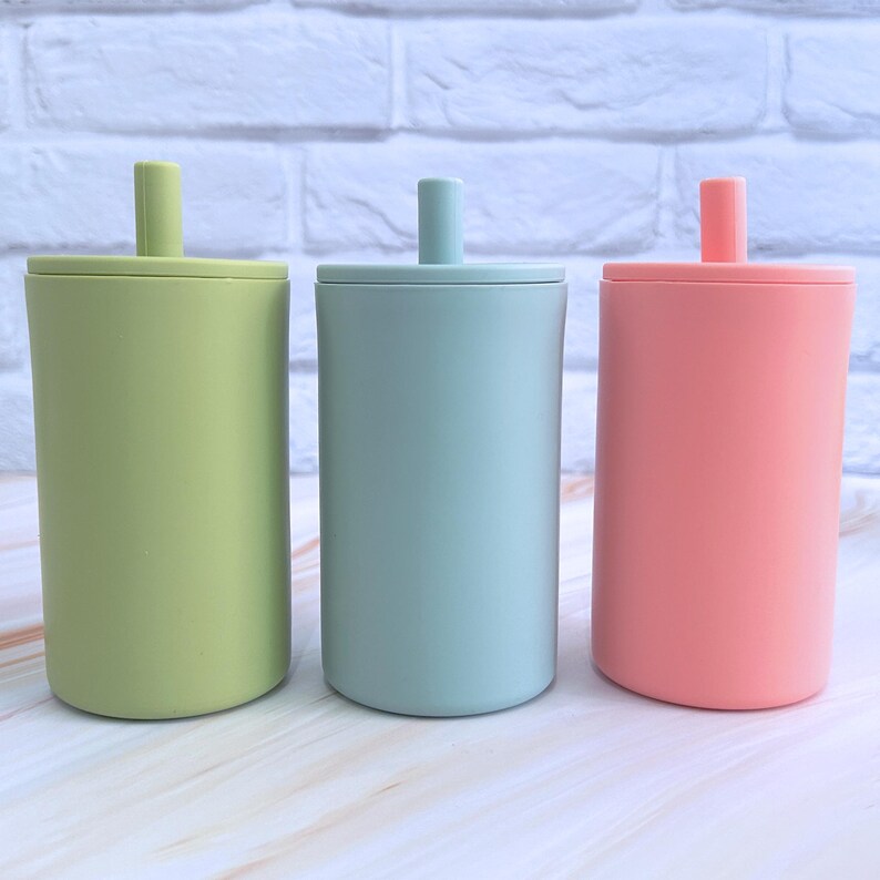 May include: Three silicone tumblers with lids and straws. The tumblers are green, blue, and pink.