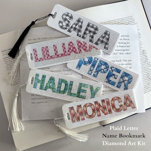 May include: A set of five diamond painting kits for bookmarks. Each kit features a different name: Sara, Lillian, Piper, Hadley, and Monica. The kits are on a white background with a white tassel.