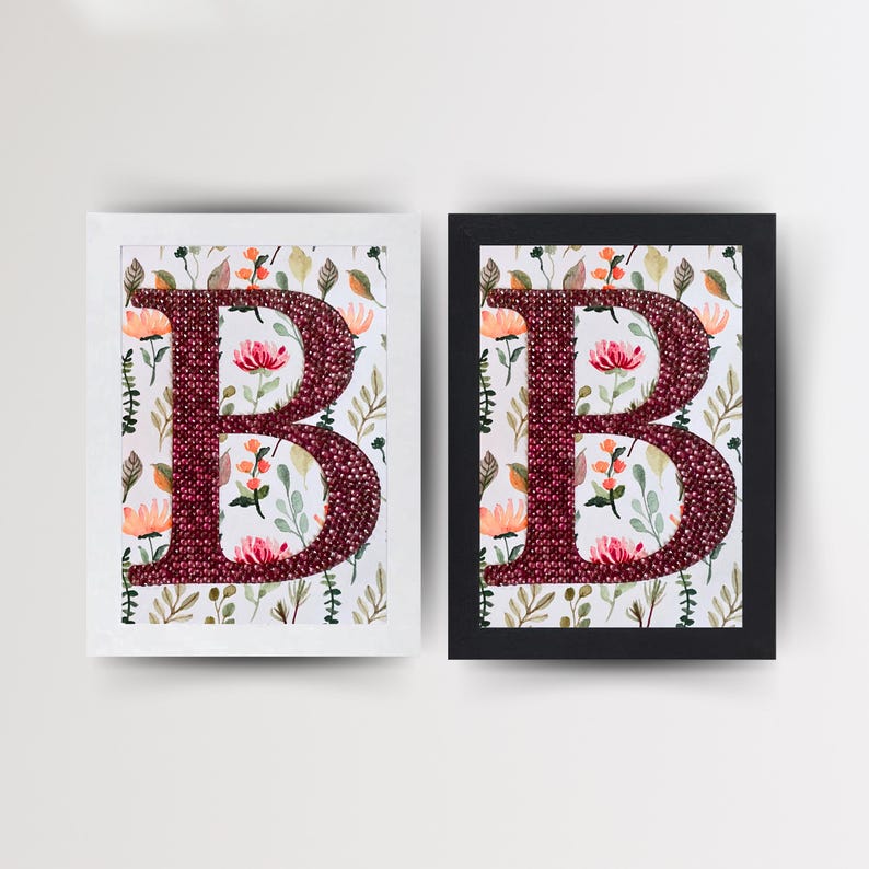 May include: Two framed pictures of the letter "B" made of red sequins on a white background with a floral pattern. The frames are white and black.