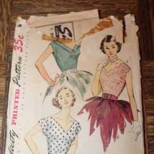 May include: Vintage Simplicity printed sewing pattern featuring illustrations of women's dresses. The pattern cover shows three dress designs in watercolor style, with the text "Simple to Make" and "35c". The pattern is slightly torn.