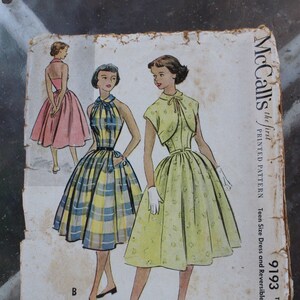 May include: Vintage McCall's sewing pattern featuring illustrations of teen dresses. The pattern shows a halter dress in a blue and yellow plaid, a yellow dress with a bolero, and a pink dress. The pattern is labeled "9193" and "Teen Size".