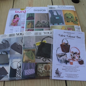 May include: A collection of six sewing patterns for handbags and accessories, including brands like Burda, McCall's, Vogue, and StoryQuilts. Each paper envelope features printed photographs of finished bags, instructional text, and brand logos.