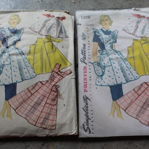 May include: Two identical Simplicity printed pattern 1358 envelopes featuring illustrations of a person wearing a blue dress with a white floral apron, a yellow apron, and a pink plaid dress. The text includes Simplicity Printed Pattern 40c.