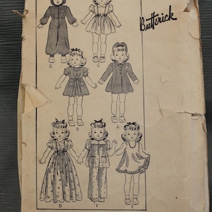 May include: A vintage Butterick sewing pattern envelope for a 14 inch doll, numbered 456. The beige paper envelope features black line illustrations of seven different doll outfits labeled A through G, including dresses, pajamas, and a hooded jumpsuit.