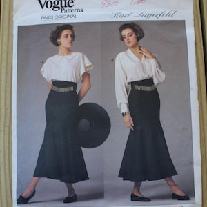 May include: A Vogue Patterns Paris Original sewing pattern envelope by Karl Lagerfeld, number 1900. The cover features two views of a white blouse paired with a high-waisted black skirt. The text includes Vogue Patterns, Paris Original, Karl Lagerfeld, and 1900.