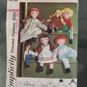 May include: A Simplicity 5714 sewing pattern envelope for fabric dolls. The front shows six illustrated dolls in various outfits, including dresses and pants. Text includes '5714', 'One Size', 'Printed Pattern 50c', and 'IN CANADA 60c'.