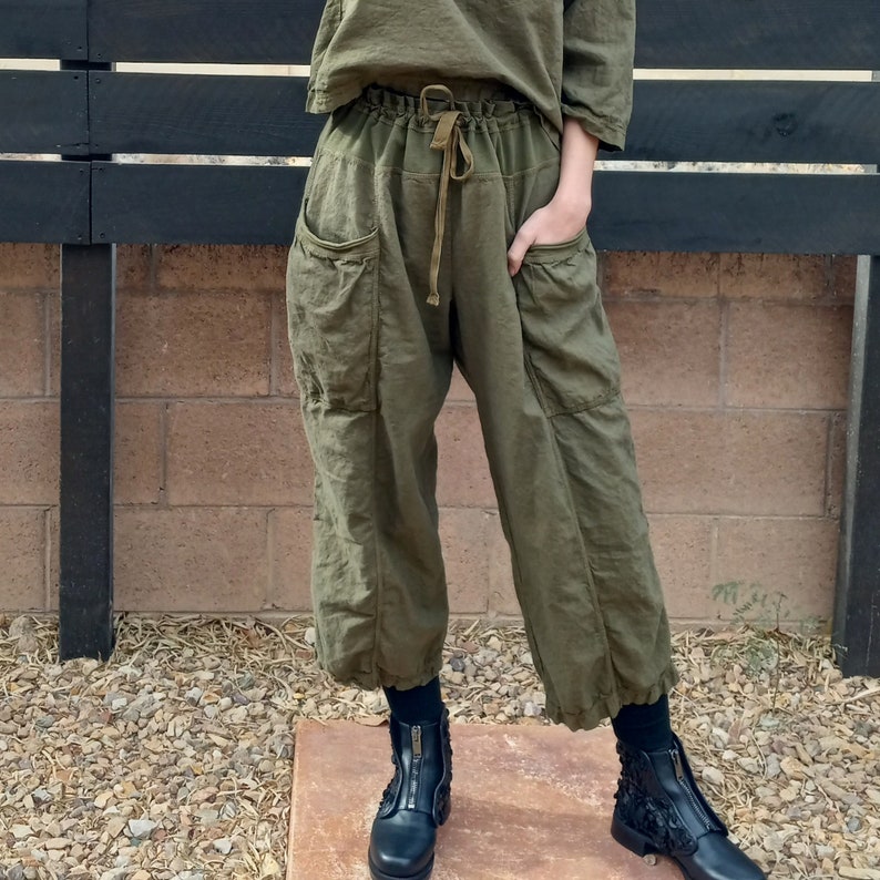 Puede incluir: Pantal&oacute;n cargo verde oliva con cintura de cord&oacute;n y bolsillos grandes. El pantal&oacute;n est&aacute; hecho de una tela ligera y tiene un corte holgado.