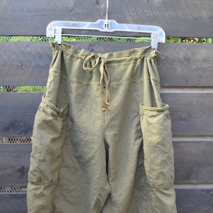 Puede incluir: Pantal&oacute;n de lino verde oliva con cintura de cord&oacute;n y grandes bolsillos cargo.