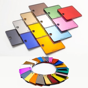 May include: Assortment of colored acrylic mirror sheets. The sheets are arranged in a pattern, with some overlapping. The sheets are all square and have a smooth, reflective surface. The colors include red, pink, blue, green, yellow, orange, silver, gold, and black.