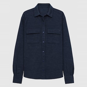 May include: A long-sleeve button-down shirt in a dark navy blue heathered fabric. The shirt features a classic collar, a front placket with matching dark blue snap buttons, and two chest pockets with flaps. The cuffs also include snap buttons.