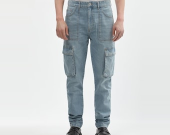May include: Light blue denim cargo pants featuring a high-waisted fit, a button and zipper fly closure, two front hip pockets, and two large rectangular cargo pockets on the thighs. The pants have a straight-leg cut and visible stitching details.