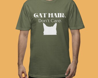 Pode incluir: Uma camiseta verde com o texto "CAT HAIR, Don't Care." em branco. Abaixo do texto, há uma silhueta branca da cabeça de um gato.