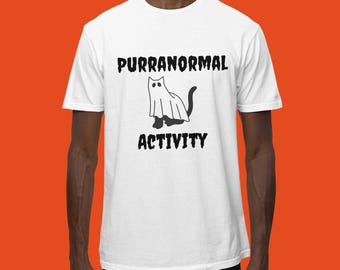 May include: White t-shirt with black text that reads "Purranormal Activity" and a black and white illustration of a ghost cat.