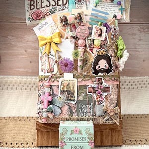 Könnte beinhalten: Eine dekorierte Holzkiste gefüllt mit religiösen Gegenständen. Die Kiste ist mit Kreuzen, floralen Verzierungen und dem Text "Simply Blessed" verziert. Außerdem gibt es eine kleine Schachtel mit dem Text "Promises From God For Women".