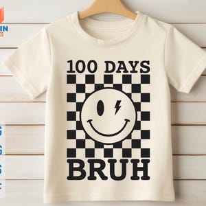 K&ouml;nnte beinhalten: Wei&szlig;es T-Shirt mit einem schwarz-wei&szlig;en Karomuster, einem Smiley mit einem Blitz und dem Text "100 Days  Bruh".