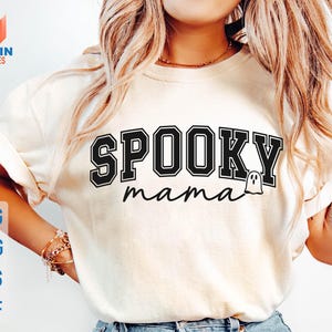 May include: Cream-colored t-shirt with the words "SPOOKY mama" in black, outlined in white. A small ghost graphic is next to the word "mama". The shirt also has the file types: SVG, PNG, EPS, and DXF.