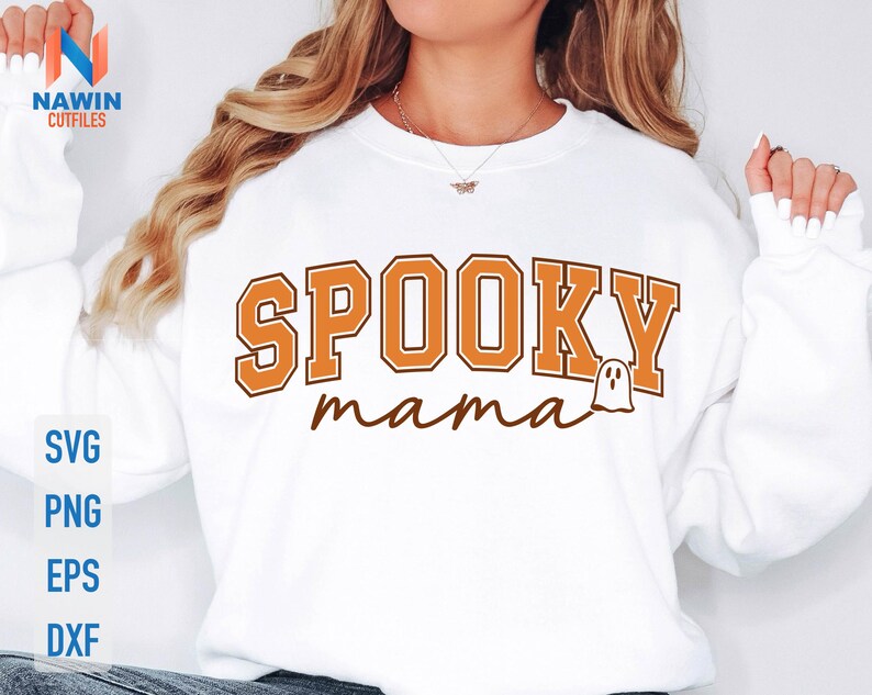 May include: White sweatshirt with the text "SPOOKY mama" in orange and brown lettering, featuring a small ghost graphic. The sweatshirt also has the words "SVG, PNG, EPS, DXF" in blue.