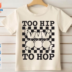 May include: White t-shirt with a black and white checkered pattern and three cartoon bunnies wearing sunglasses. The text "Too Hip To Hop" is printed on the shirt.