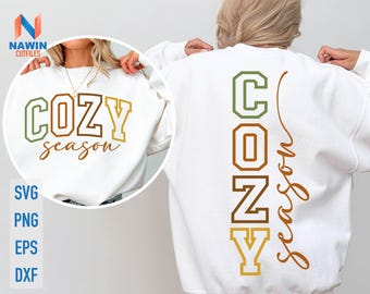 May include: White sweatshirt with the words "COZY season" in a mix of green, brown, and gold lettering on the front. The back of the sweatshirt has the word "COZY" vertically and "Season" in a cursive font.