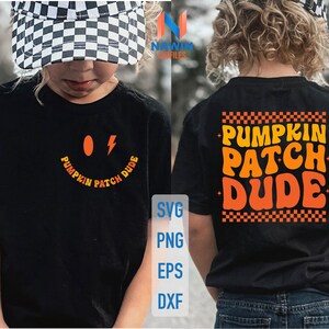Pode incluir: Camiseta preta com o texto "Pumpkin Patch Dude" em laranja e amarelo. A frente da camiseta apresenta um desenho de rosto sorridente com um oval laranja e um raio. A parte de trás da camiseta tem o mesmo texto em uma fonte retrô.