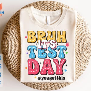 May include: A white t-shirt with a colorful graphic that says "Bruh It's Test Day #yougotthis".