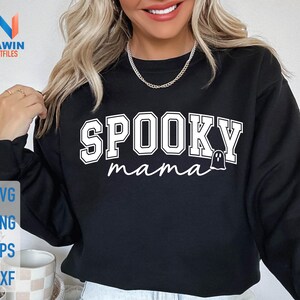 May include: Black sweatshirt with the words "SPOOKY mama" in white block letters and a ghost graphic. The sweatshirt also has the words "SVG, PNG, EPS, DXF" in a vertical stack on the left side.