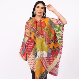 Puede incluir: Un poncho de patchwork con capucha, con una vibrante mezcla de colores que incluye rojo, amarillo, naranja y verde. El poncho tiene un cuello con cordón y un diseño suelto y fluido. La prenda está hecha de varios parches de tela.