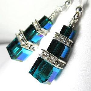 May include: A pair of dangle earrings with emerald green crystal beads and silver accents. Each bead is accented with clear rhinestones.