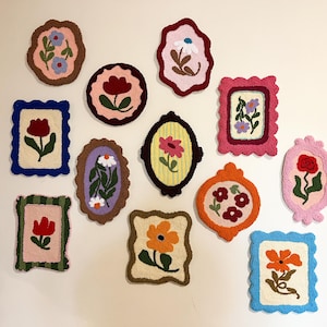 Pode incluir: Uma cole&ccedil;&atilde;o de obras de arte floral emolduradas e coloridas. Cada pe&ccedil;a apresenta um design floral diferente, com formas e tamanhos variados. As molduras s&atilde;o em tons de rosa, azul, laranja e verde, criando uma exibi&ccedil;&atilde;o vibrante. A arte &eacute; provavelmente feita de um material texturizado.