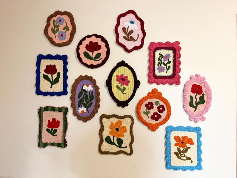 Pode incluir: Uma cole&ccedil;&atilde;o de obras de arte floral emolduradas e coloridas. Cada pe&ccedil;a apresenta um design floral diferente, com formas e tamanhos variados. As molduras s&atilde;o em tons de rosa, azul, laranja e verde, criando uma exibi&ccedil;&atilde;o vibrante. A arte &eacute; provavelmente feita de um material texturizado.