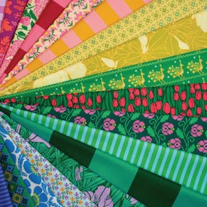 May include: A fan of various fabric swatches in a spectrum of colors. The fabrics display floral, striped, and geometric patterns in shades of pink, yellow, green, and blue. The arrangement showcases the diversity of textile designs.