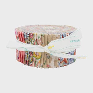 May include: A roll of colorful fabric strips, featuring floral and patterned designs in pink, beige, and blue hues. The fabric is tied with a white ribbon that has the text "#RileyB".