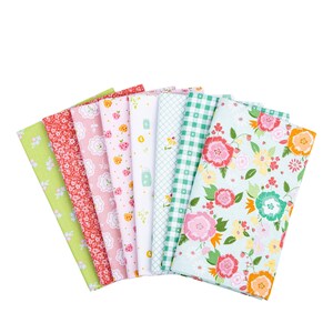 May include: A collection of colorful fabric swatches fanned out against a white background. The fabrics feature various floral and patterned designs in shades of pink, green, and white. The fabrics are likely cotton or a similar material.