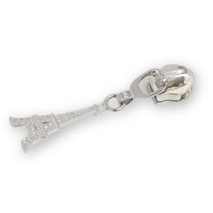 May include: Silver-colored zipper pull with a detailed Eiffel Tower charm. The zipper pull is made of metal and features a classic design. The charm is a miniature replica of the Eiffel Tower, adding a touch of Parisian flair.