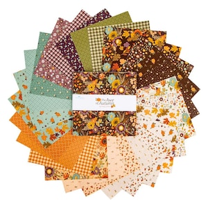 May include: A stack of square fabric swatches arranged in a circular fan pattern. The fabrics feature autumn-themed prints including pumpkins, sunflowers, leaves, and plaid patterns in orange, brown, green, and cream. A white paper band reads The Awe of Autumn.