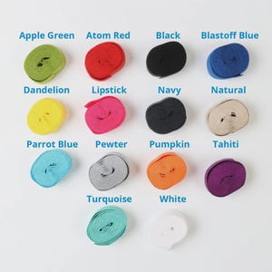May include: A collection of spools of ribbon in various colors, including Apple Green, Atom Red, Black, and Blastoff Blue. Other colors include Dandelion, Lipstick, Navy, Natural, Parrot Blue, Pewter, Pumpkin, Tahiti, Turquoise, and White.