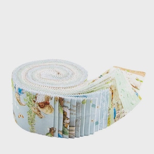 May include: A rolled bundle of fabric strips featuring a light blue background with illustrations of rabbits, flowers, and text. The fabric is rolled up, with the edges of the strips visible, showcasing a variety of patterns and colors.