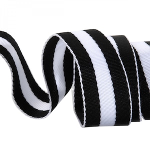 May include: Close-up of a black and white striped ribbon. The ribbon is tightly woven with alternating thick stripes of black and white. The ribbon is curled and twisted, creating a dynamic visual.