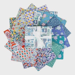 May include: A collection of colorful fabric squares arranged in a circular pattern. The fabrics feature various floral, geometric, and architectural designs in shades of blue, red, yellow, and green. A white ribbon wraps a central bundle.