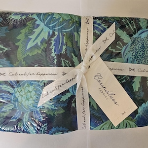 May include: A fabric bundle wrapped in clear plastic, tied with a white ribbon and tag. The fabric features a blue, green, and teal floral pattern. The ribbon reads "Cut out for happiness" and the tag says "Boundless Fabrics".